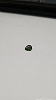 Pear cut bright green sapphire on white background showing color and facets