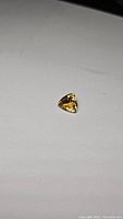 Clear image showing the triangular trillion cut shape of the deep golden citrine gemstone with visible facets.