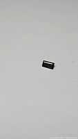 Single bright green baguette cut natural tourmaline gemstone on white background, showing the length and color of the stone.