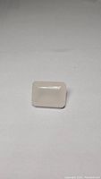 Front view photo of a large soft pink rose quartz emerald cut gemstone on a plain background.