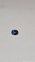 Oval tanzanite gemstone face-up on plain white background
