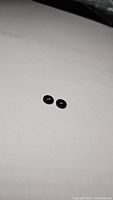 Pair of small oval jet black onyx stones on white background, showing size and polish.