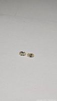 Two small oval light champagne colored zircon gemstones, each approximately 6x4mm, displayed on a white background in natural light.