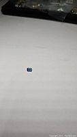 Small emerald cut London Blue Topaz gemstone on a white background showing its rich blue color and facet cuts