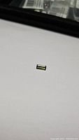 Clear photo of a single mint green baguette cut tourmaline gemstone on white background showing color and cut.