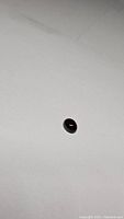 Oval cabochon deep red garnet gemstone on white background, showing smooth polished surface and rich color.