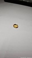 Natural golden citrine oval cut gemstone lying flat on a neutral background, showing color and cut facets