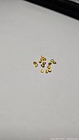 Parcel of 15 small pear cut sapphires in multiple vibrant shades including orange yellow and green on a white background.