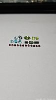 Top down photo of 21 faceted mixed gemstones laid out on white background.