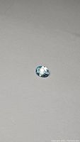 Oval cut natural sky blue topaz gemstone on neutral background showing facets and color