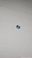 Oval cut natural Swiss blue topaz gemstone on white background, showing blue color and faceting details, first angle