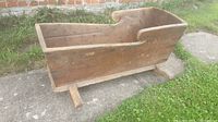 Side view showing the length and construction of the wooden cradle with rocker legs and curved cutout on the side panel.