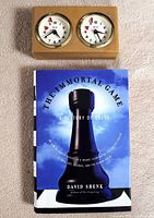 Photo of the chess timer and the front cover of the book titled 'The Immortal Game: A History of Chess' by David Shenk.
