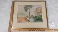 Framed watercolour landscape showing tree, curved stone bridge, water, and building with measuring rulers indicating frame size.