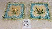 Pair of Victorian tiles in pale green metal holders on light fabric surface