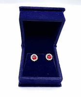Front view of ruby and white sapphire stud earrings in blue velvet box.
