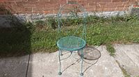 Front angle view of the vintage metal chair showing the curved backrest and perforated seat