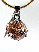 Close-up of yellow topaz cube-shaped pendant showing facets and white gold-plated mount.