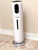 Full view of white column ZXBEER ultrasonic humidifier standing on tiled floor, showing power cord and water level window.