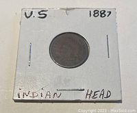 Front photo showing the 1887 US Indian Head one cent coin in a white cardboard holder with handwritten labels.