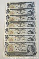 Seven Canadian one-dollar bills from 1973, front side visible, showing sequential serial numbers.