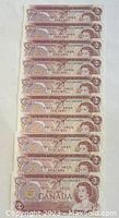 Photo of all 10 Canadian 1974 $2 bills stacked to show the front side with sequential serial numbers visible.