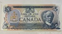 Front side of 1979 Canadian $5 banknote showing portrait of Sir Wilfrid Laurier and coat of arms.