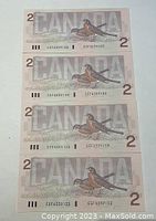 Four sequentially numbered 1986 Canadian $2 bills back side showing robin bird and large 'CANADA' text in subtle security pattern.