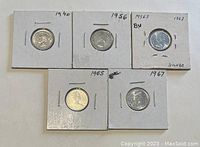 Five Canadian 10 cent coins dated 1940, 1956, 1963, 1965, 1967 mounted in white holders with year and metal content written