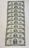 Front view of ten sequential $2 bills showing faces and serial numbers.