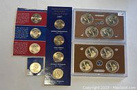 Three sets of US Mint Presidential $1 coins proof sets from 2007, 2008, 2012 with four additional individual coins laid out showing packaging and coin faces.