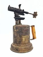 Side view of an antique plumber torch showing metal body, wooden handle, and perforated burner head with valve knob.