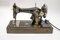Side view of black Singer sewing machine showing floral decals and gold branding on wooden base