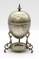 Full view of antique silver plated egg-shaped covered servingware with finial on lid and ornate stand on circular base