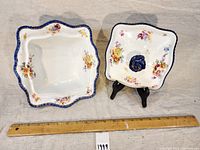 Photo of vintage square porcelain tureen and its matching lid with floral patterns and blue rose handle, alongside a ruler for scale.