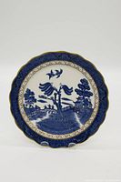 Front view of the vintage Blue Willow decorative plate with intricate blue pattern and gold rim.