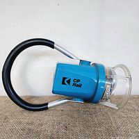 Blue CP Rail lantern with black handle and clear protective cover on a brown textured surface.