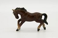Side view of brown glossy ceramic horse figurine, showing detailed mane and tail, light shading on legs and face.