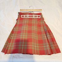 Front view of vintage kilt hung with measuring ruler showing size and length with classic tartan pattern.