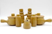 Whole set of vintage MCM pottery tableware with warm brown glaze showing ribbed textured design and various shapes including covered pots, jars, and candelabra.