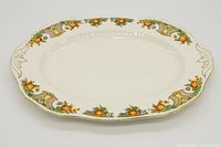 Top view of an oval vintage ceramic serving platter with floral pattern and gold accents on rim and handles.