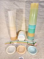 Photo of vintage Tupperware float cups stacked in pastel shades, matching pastel curved spoons bundled together, and three small round trays with star pattern on base.