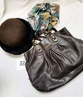 Photo of brown leather Coach bag, brown felt hat with fuzzy brim, and colorful scarf with gold fasteners arranged on white background