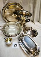 Full set arranged showing silver-plated tray, wine bucket with grape motif, covered dish, casserole holder with Pyrex insert and lids, and silver baby cup with engraving