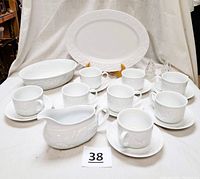 Full set of Lenox Garden Vine white embossed dishes including 8 cups and saucers, serving platter, oval vegetable dish, gravy boat, and glass evergreen salt and pepper shakers arranged on a white cloth background.