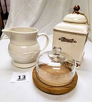 Photo of all three items: white Longaberger pitcher, Biscotti cookie jar, teak board with glass dome