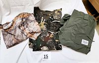 Three items laid flat: short sleeve camouflage shirt with Real Tree logos, long sleeve camouflage shirt, and green zip-off pants