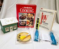 Full lot showing music box, cookbooks, grater plate set, garlic peeler in packaging, and icing kits.
