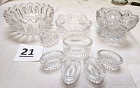Nine pieces total: one large oval salt cellar, four smaller matching salt cellars, one uniquely designed smaller salt cellar, and three cut glass bowls arranged on table