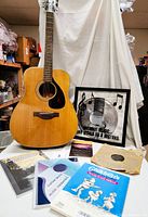 Front view of guitar, record, books and framed art on table